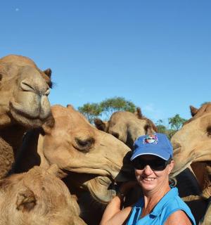 一位妇女站在一群骆驼前