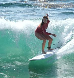 dívka jedoucí na vlně na surfovém prkně v oceánu