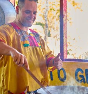 a man cooking food in a pan on a stove
