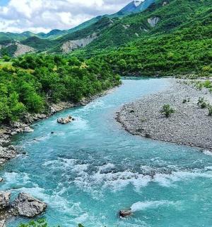 a river with blue water and rocks and mountains
