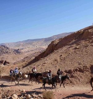 skupina lidí jezdících na koních v poušti