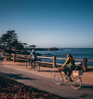 people riding bikes on a path near the ocean