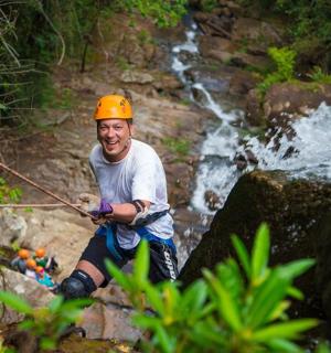 a man in a helmet standing on a rope over a waterfall