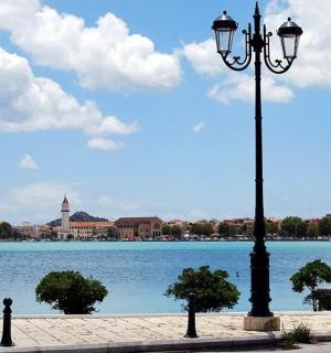 a street light next to a lake with people sitting on a bench
