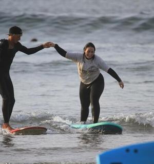 两名女子站在海里的冲浪板上