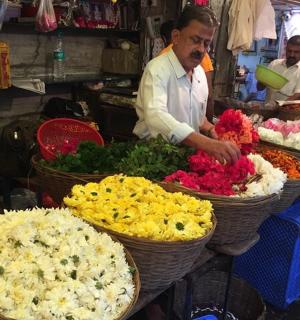 muž připravuje květiny do košů na trhu