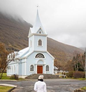 žena procházející kolem bílého kostela s věží