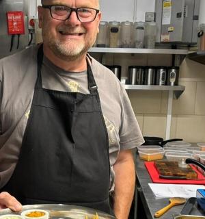 a man in a kitchen holding a plate of food