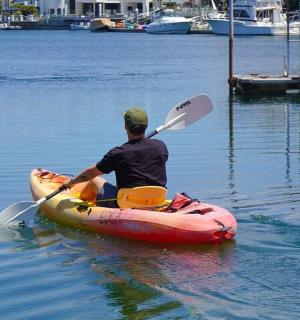 muž v kajaku na vodě s pádlem