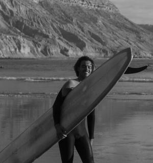 a woman standing on the beach holding a surfboard