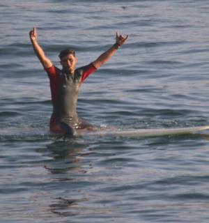 一名男子坐在水中的冲浪板上