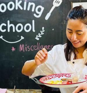 一位女士端着一盘食物站在黑板前