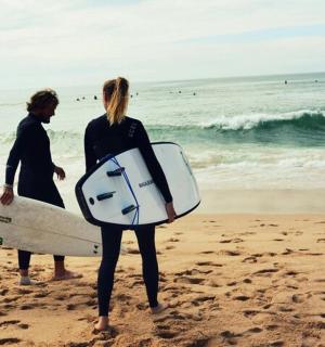 两个人站在海滩上,手里拿着冲浪板