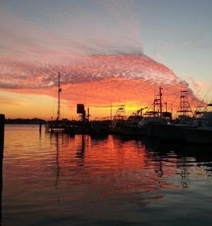 Skupina lodí zakotvených v molu se západem slunce