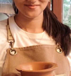 seorang wanita dalam apron memegang mangkuk tanah liat