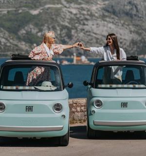 Dvě ženy sedí v malém autě s nataženýma rukama