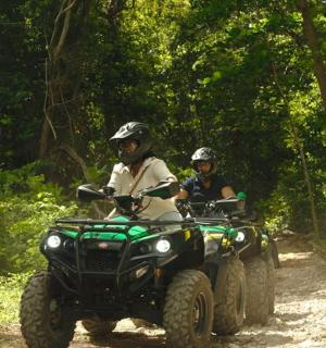 两个人骑着四轮摩托车在泥路上行驶
