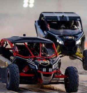 dvě čtyřkolky skákající do špíny na prašné cestě