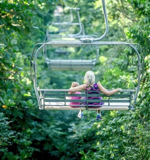 一名女子坐在树上的滑雪缆车上