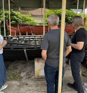 um grupo de pessoas em pé na frente de um barco