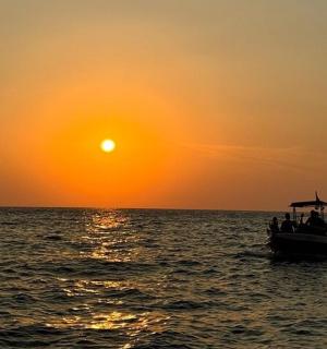 a group of people on a boat in the ocean at sunset