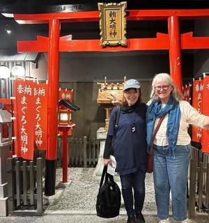 两名女子站在红色鸟居门前