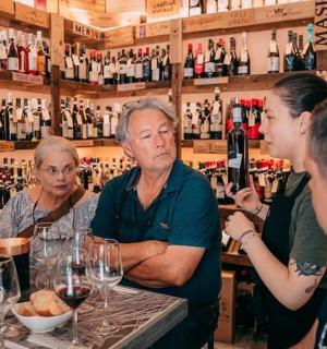 skupina lidí stojících kolem baru s vinnými sklenicemi