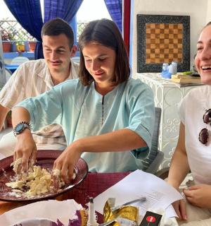 three people sitting at a table with a plate of food
