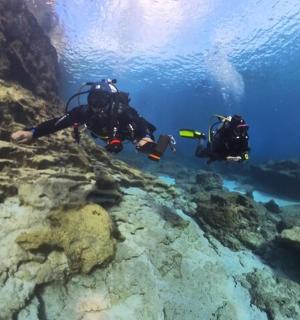 dva lidé v potápěčském vybavení plavou v oceánu