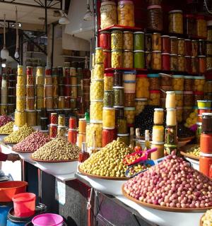 muž stojící před trhem se spoustou jídla