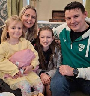 一名男子、一名女子和两个孩子坐在沙发上