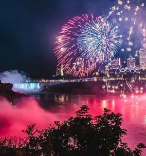 a fireworks display over a river with a city in the background