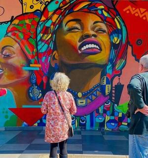 skupina lidí stojících před nástěnnou malbou