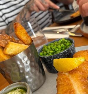 桌子上摆着一盘炸鱼和豌豆