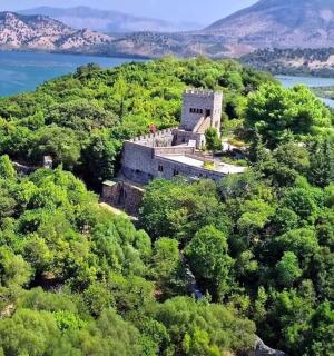an old castle on a hill with trees and water