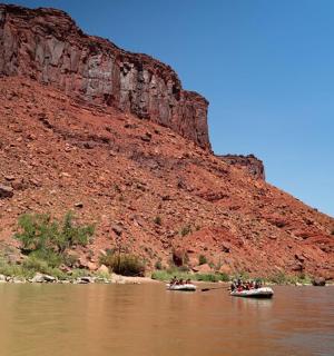 a group of people in canoes on a river next to a mountain