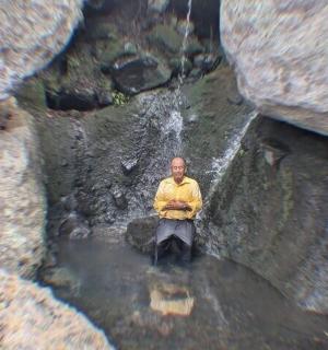 一名男子坐在水中的一块岩石上