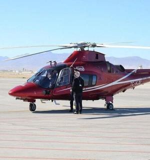 a man standing in front of a red helicopter