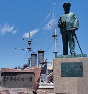 a statue of a man standing in front of a ship