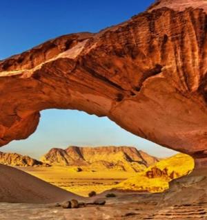 an arch in the desert with mountains in the background