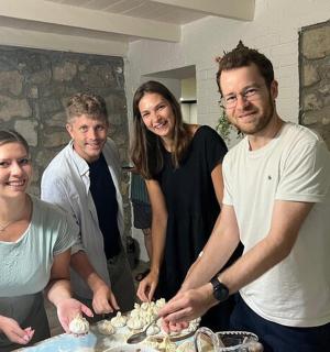 a group of people standing around a table with a cake