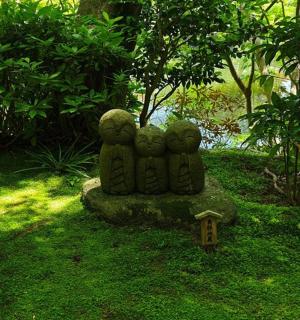 草地上岩石上坐着三个人的雕像