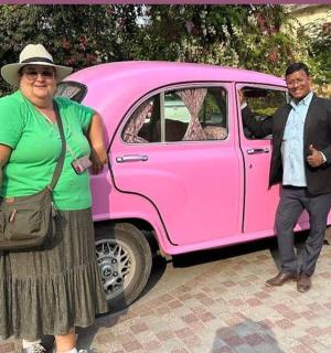 muž a žena stojící vedle růžového auta