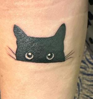 en sort kat-tatovering på en kvindes ankel