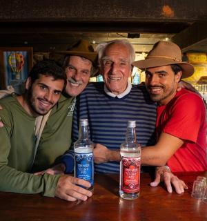 skupina mužů stojících kolem baru s lahvemi od limonády