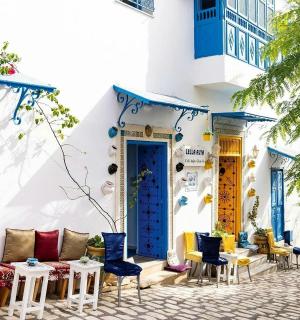 a building with blue doors and chairs on a street