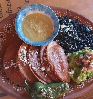 a plate of food with beans and a bowl of dip