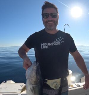 a man standing on a boat holding a fish