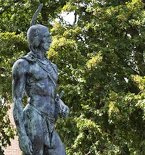 socha ženy stojící před stromy