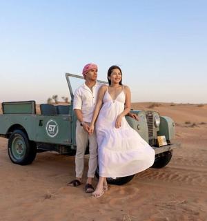 a man and a woman standing next to a car in the desert